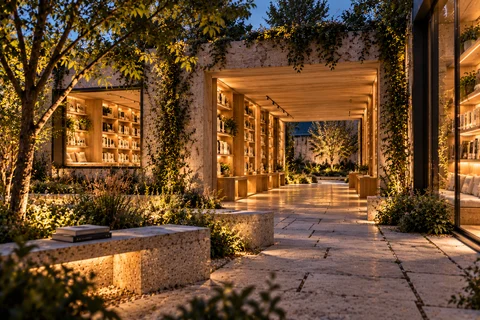 Vue du jardin et de la micro-bibliothèque éclairée au crépuscule.