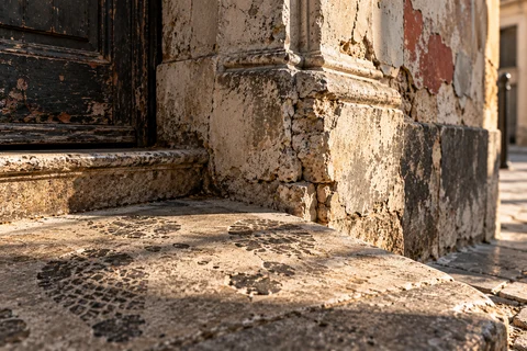 Marches et seuil en pierre usée, au pied d’un mur ancien.